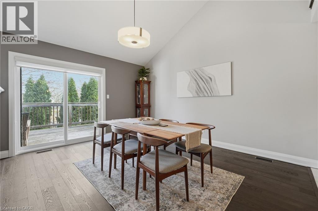 Dining area featuring a vaulted ceiling, wood-finish flooring, and a sliding glass door opening to an exterior deck - 7 Gibson Place Unit# 26, St. Catharines, ON - Indoor Photo Showing Dining Room