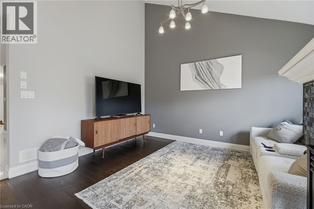 Living area featuring soaring ceiling height, dark wood-finish flooring, and a contemporary multi-light fixture - 7 Gibson Place Unit# 26, St. Catharines, ON - Indoor