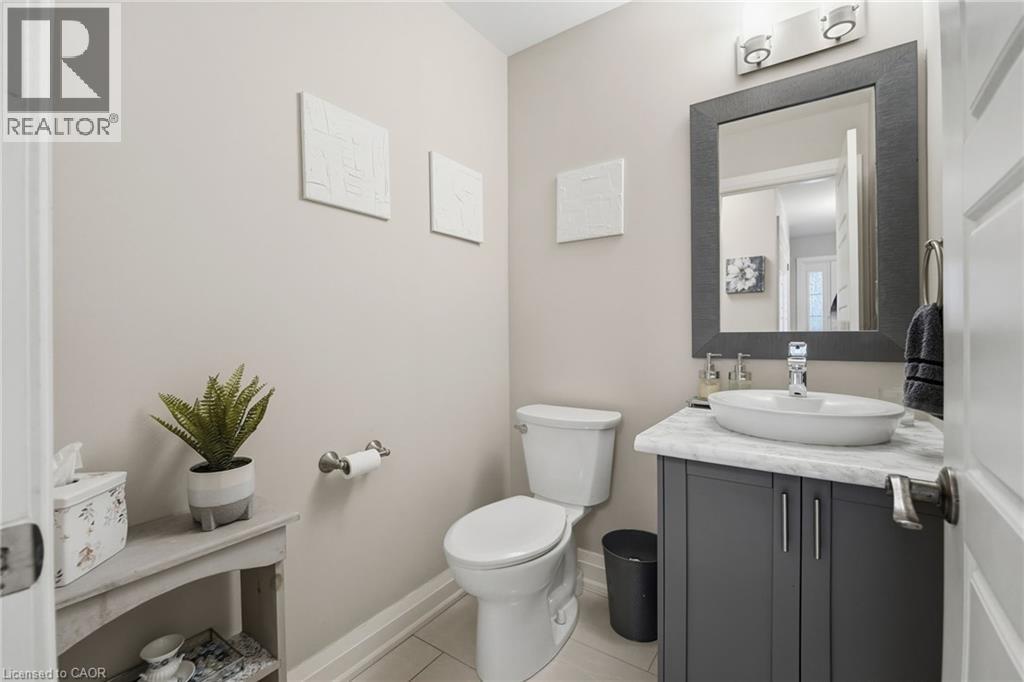 Modern powder room featuring a gray vanity with a vessel sink, a white countertop, and contemporary wall sconces - 7 Gibson Place Unit# 26, St. Catharines, ON - Indoor Photo Showing Bathroom