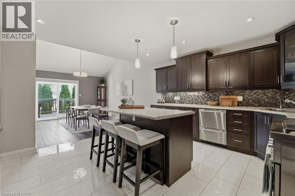 Open-concept kitchen with dark wood cabinetry, stainless steel appliances, and a mosaic tile backsplash - 7 Gibson Place Unit# 26, St. Catharines, ON - Indoor Photo Showing Kitchen With Upgraded Kitchen