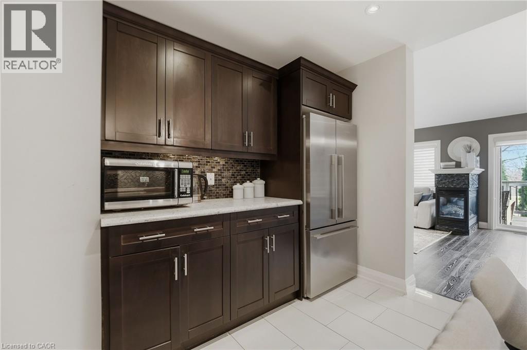 Kitchenette featuring dark wood-finish cabinetry, stainless steel refrigerator, and built-in microwave - 7 Gibson Place Unit# 26, St. Catharines, ON - Indoor Photo Showing Kitchen