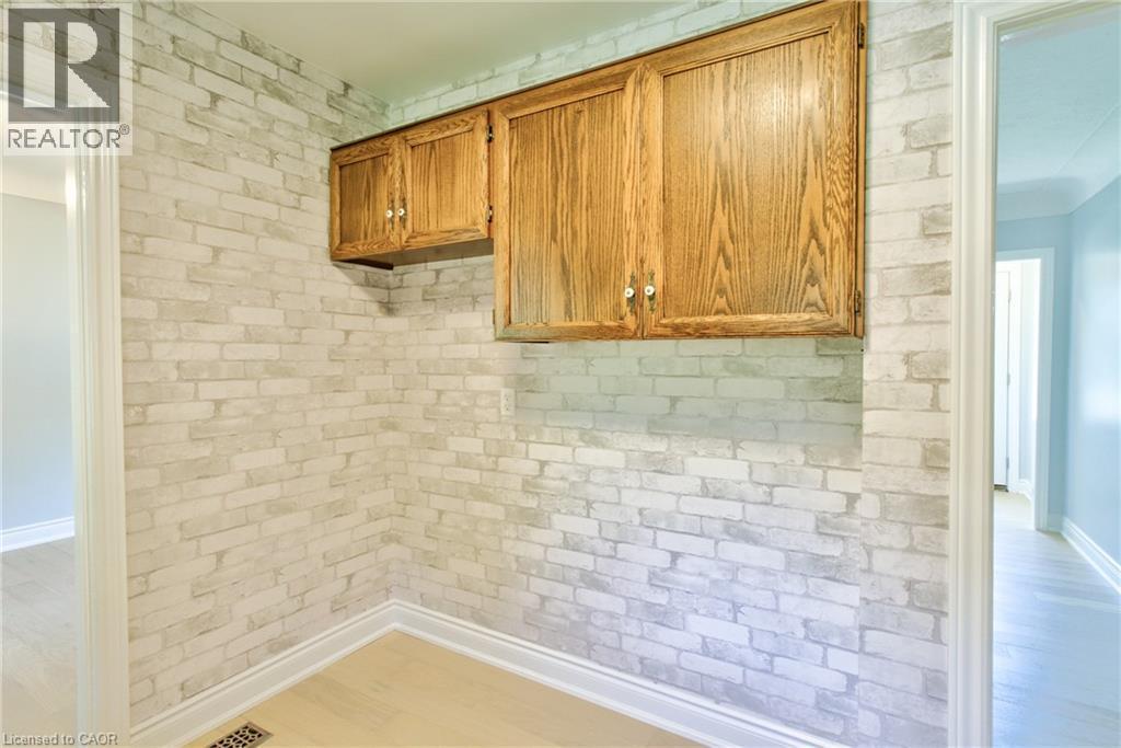 Wall-mounted cabinetry with wood-finish doors and brushed nickel hardware - 31 Brodick Street, Hamilton, ON - Indoor Photo Showing Other Room