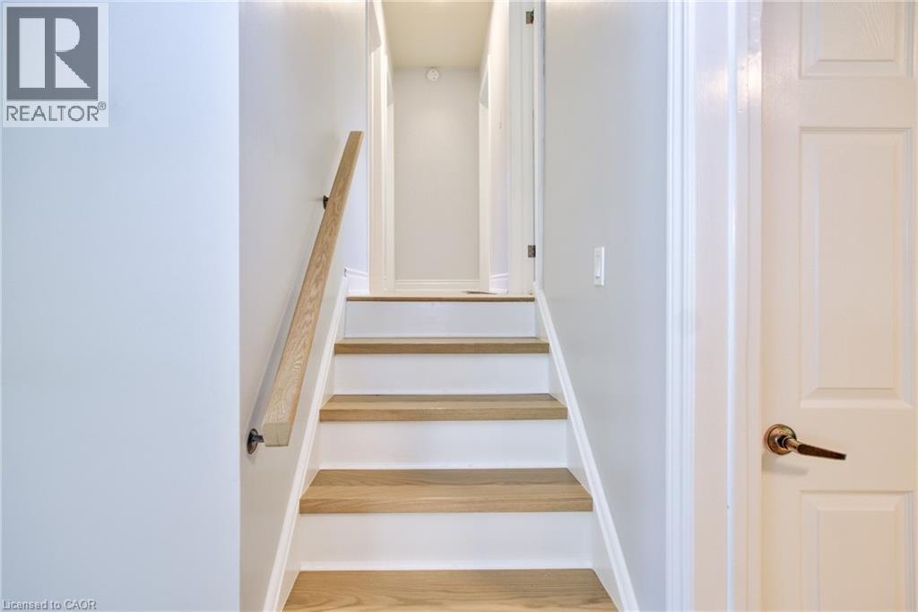 Staircase featuring wood-finish treads, white risers, and a natural wood handrail - 31 Brodick Street, Hamilton, ON - Indoor Photo Showing Other Room