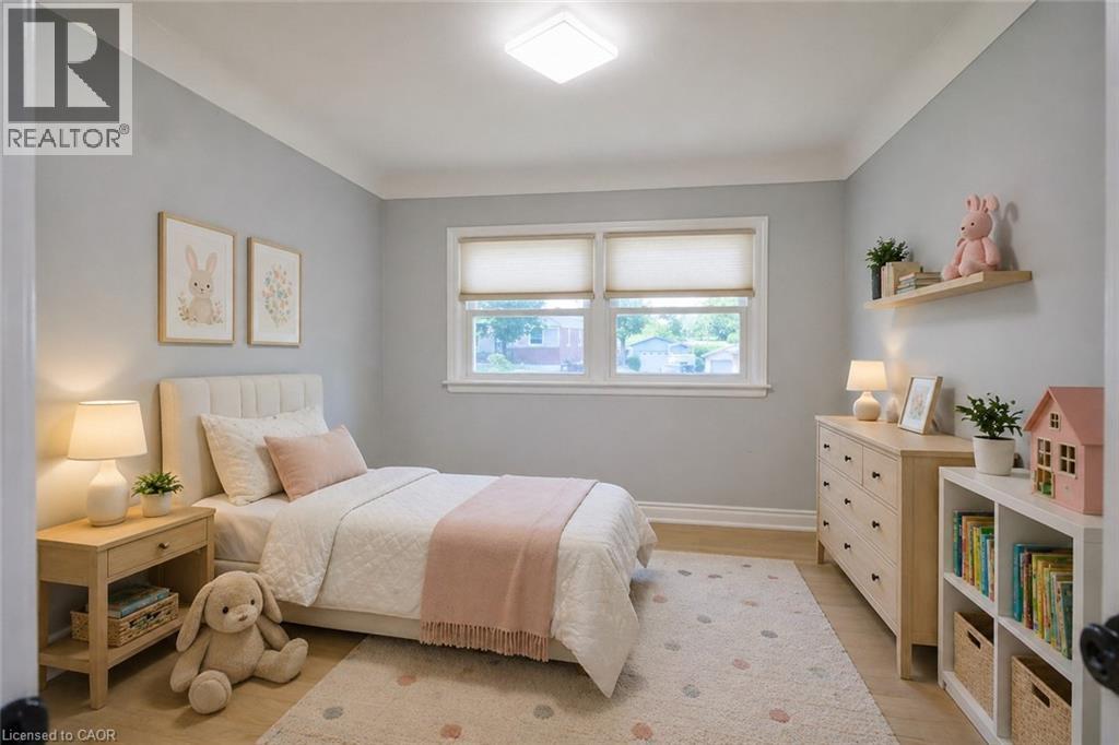 Bright interior space featuring light wood-finish flooring, two large windows with roller shades, and a white ceiling with crown molding - 31 Brodick Street, Hamilton, ON - Indoor Photo Showing Bedroom