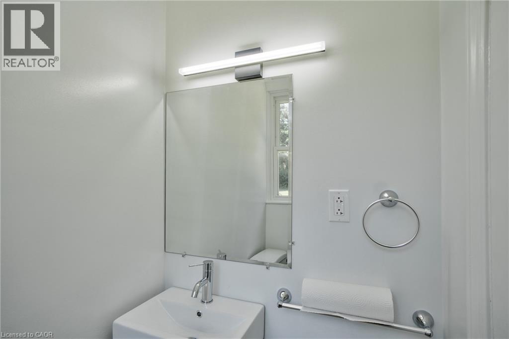 Modern bathroom vanity featuring a rectangular vessel sink with chrome faucet, illuminated by a contemporary linear light fixture - 31 Brodick Street, Hamilton, ON - Indoor Photo Showing Bathroom