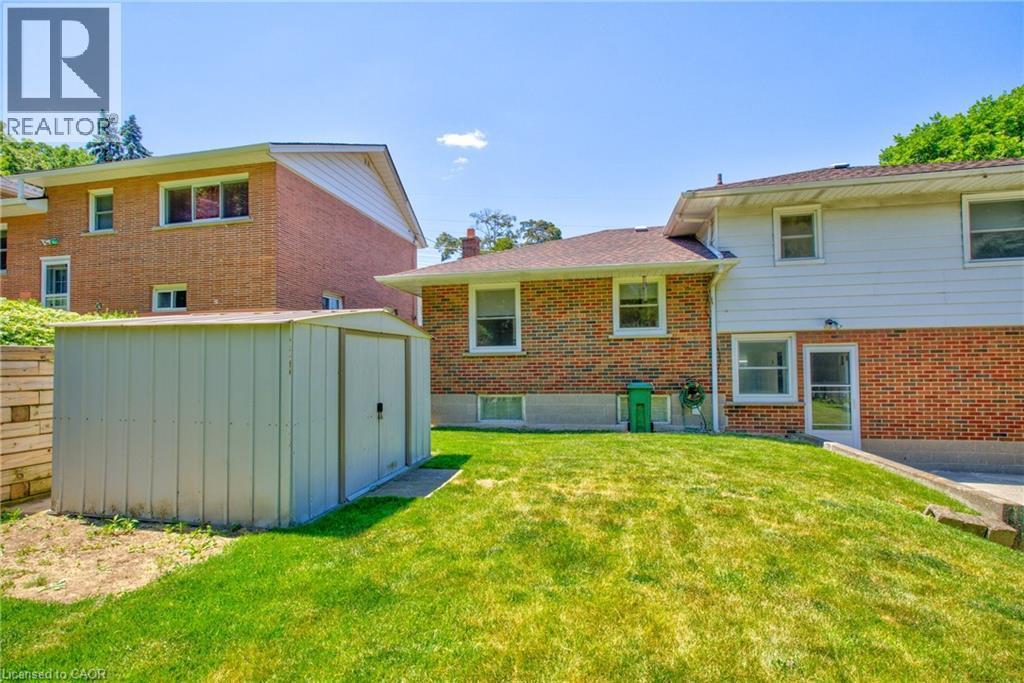 Expansive rear yard featuring a large storage shed on a concrete base, a sloped lawn, and a retaining wall - 31 Brodick Street, Hamilton, ON - Outdoor With Exterior
