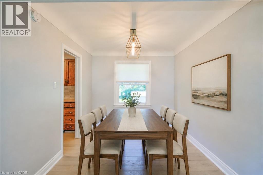 Dedicated dining area featuring wood-finish flooring, a contemporary geometric pendant light, and a window with a roller shade - 31 Brodick Street, Hamilton, ON - Indoor Photo Showing Dining Room