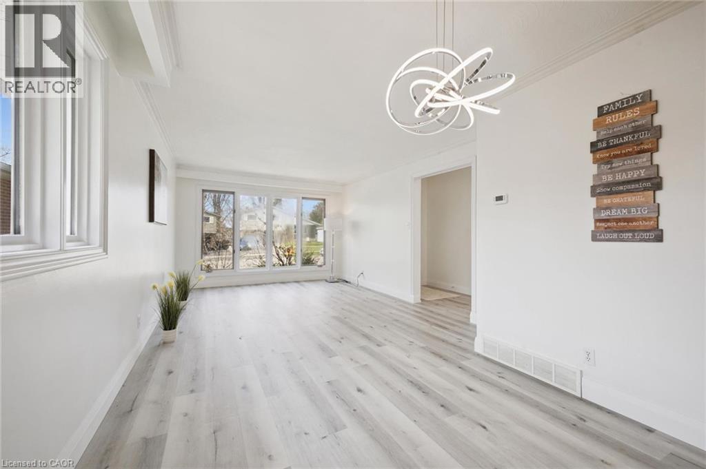 Bright interior space featuring light wood-finish flooring, white walls, and a modern circular chandelier - 27 Silverspring Crescent, Kitchener, ON - Indoor
