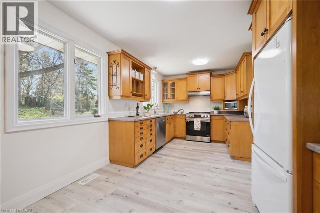 Kitchen featuring light wood cabinetry, stainless steel appliances, a white tile backsplash, and light wood-finish flooring - 27 Silverspring Crescent, Kitchener, ON - Indoor Photo Showing Kitchen