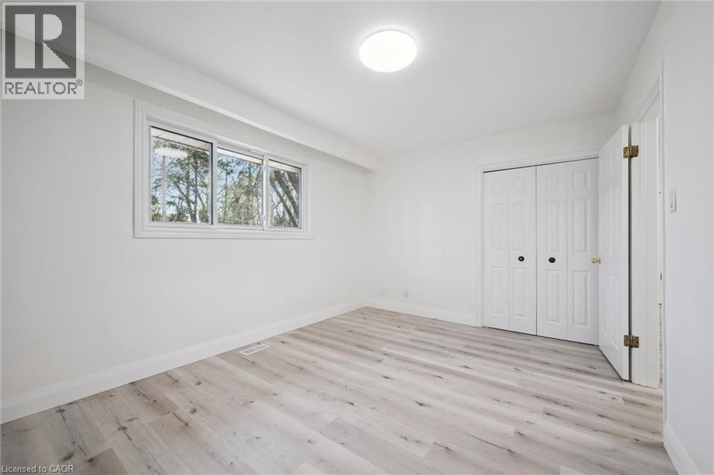 Bright interior space featuring light wood-finish flooring, white baseboards, and a contemporary flush-mount ceiling light - 27 Silverspring Crescent, Kitchener, ON - Indoor Photo Showing Other Room