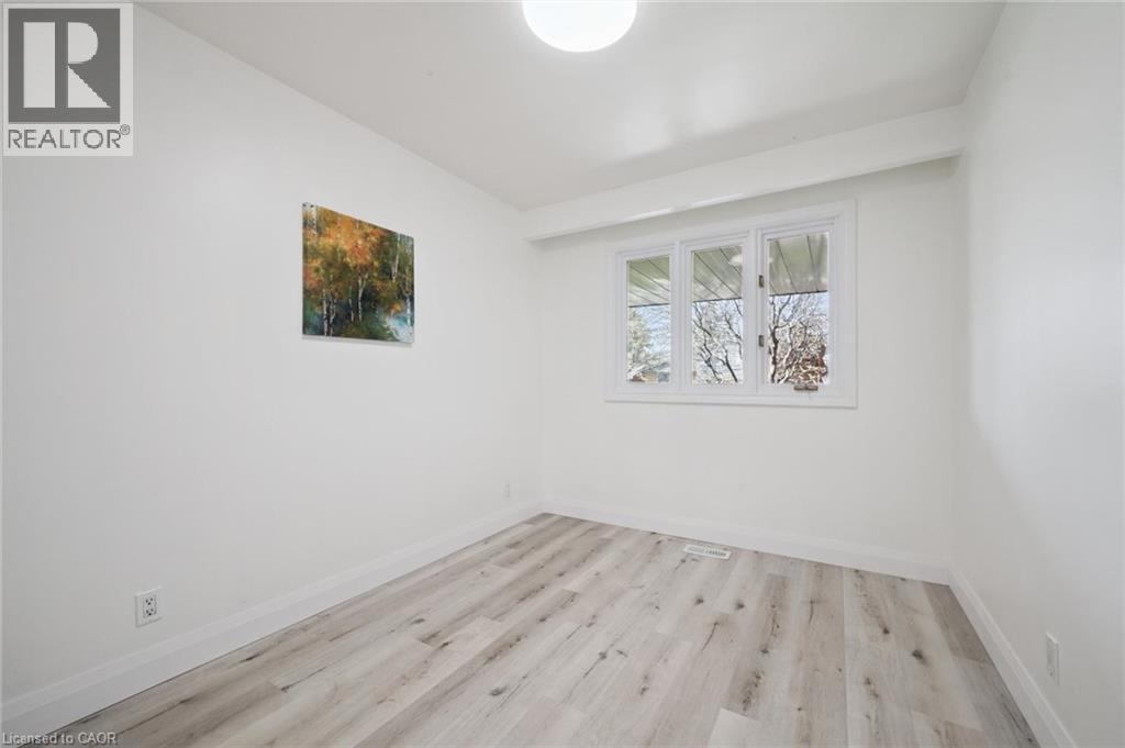 Bright interior space featuring light wood-finish flooring, white baseboards, and a triple-pane window - 27 Silverspring Crescent, Kitchener, ON - Indoor Photo Showing Other Room
