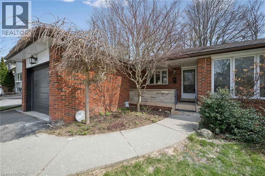 Brick exterior featuring a dark garage door, large picture windows, and a concrete walkway - 27 Silverspring Crescent, Kitchener, ON - Outdoor