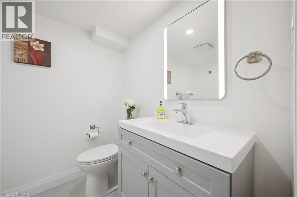 Bathroom featuring a vanity with a light gray cabinet, white integrated sink, and an illuminated rectangular mirror - 27 Silverspring Crescent, Kitchener, ON - Indoor Photo Showing Bathroom