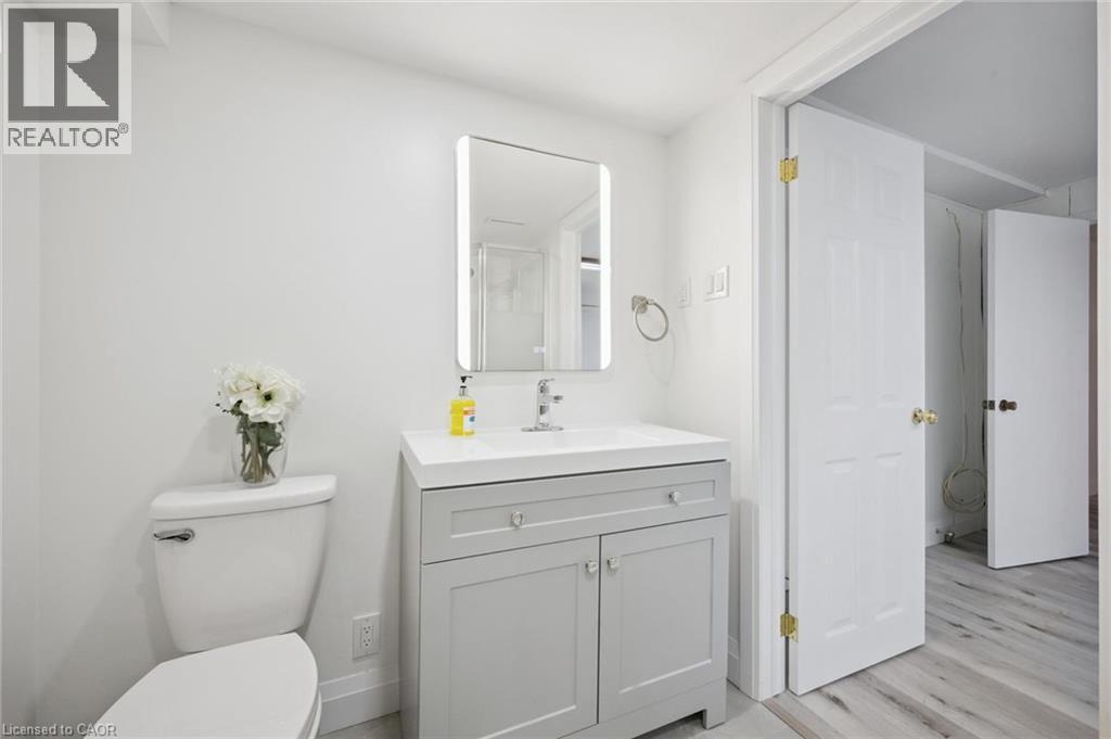 Bright bathroom featuring a contemporary vanity with an integrated sink, illuminated mirror, and light wood-finish flooring - 27 Silverspring Crescent, Kitchener, ON - Indoor Photo Showing Bathroom