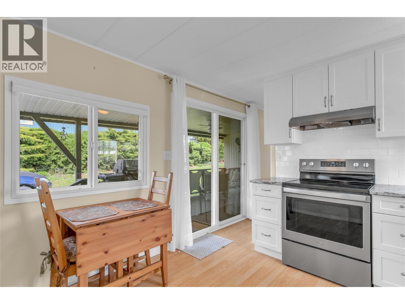 View of kitchen with the entry door and deck in the background. Eating nook with a great view of the yard. - 12022 Pretty Road Unit# 16, Lake Country, BC