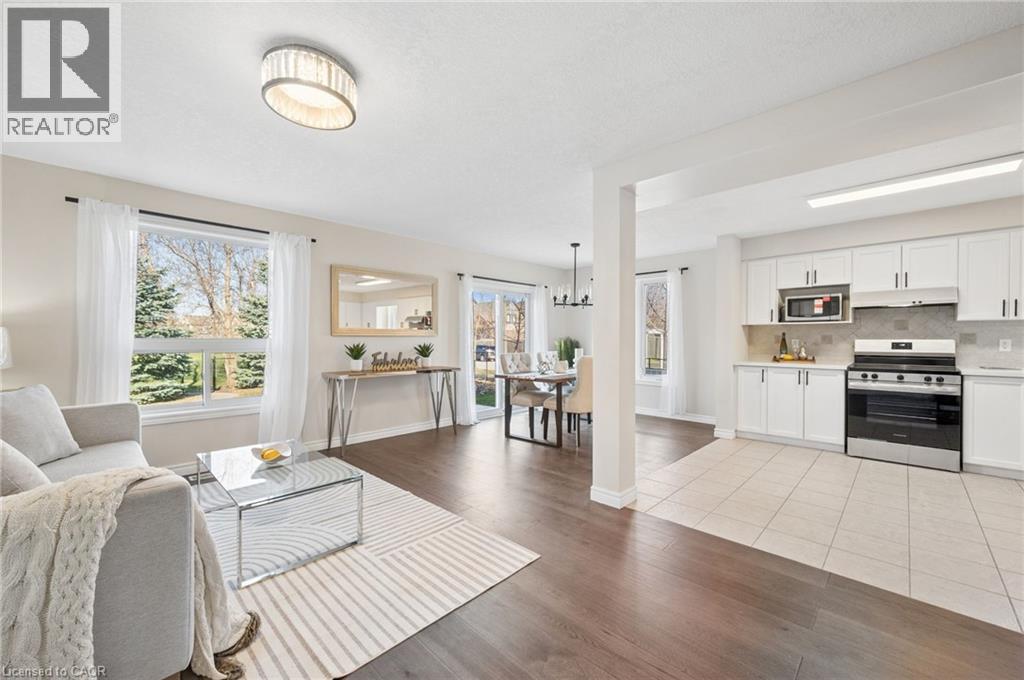 Living room featuring light wood-type flooring, a chandelier, and healthy amount of natural light - 649 Doon South Drive, Kitchener, ON - Indoor Photo Showing Other Room