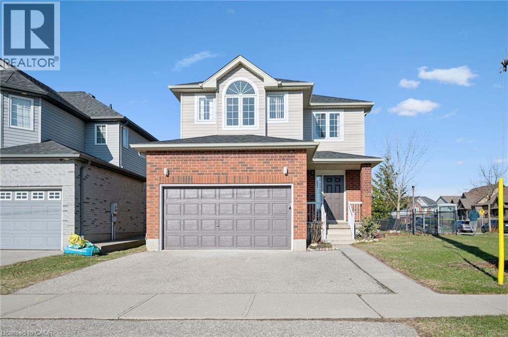 Traditional home with brick siding, asphalt driveway, a front lawn, and an attached garage - 649 Doon South Drive, Kitchener, ON - Outdoor