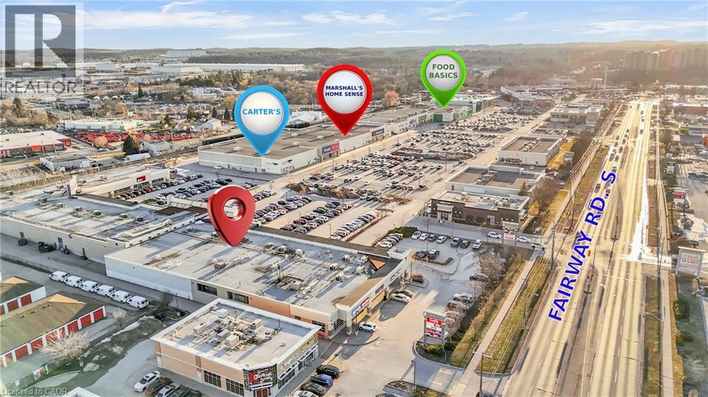 Aerial perspective of a commercial district featuring multiple retail establishments and extensive parking areas - 589 Fairway Road S, Kitchener, ON