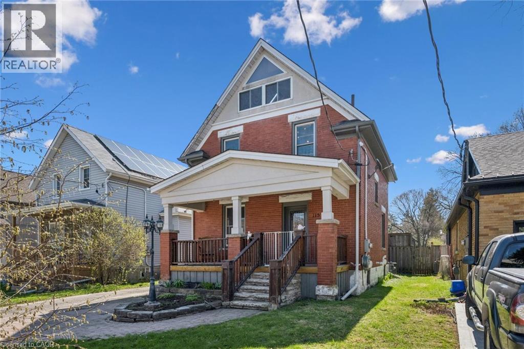 Brick exterior with a covered front porch featuring white columns and a dark railing - 115 Allen Street E, Waterloo, ON - Outdoor With Deck Patio Veranda