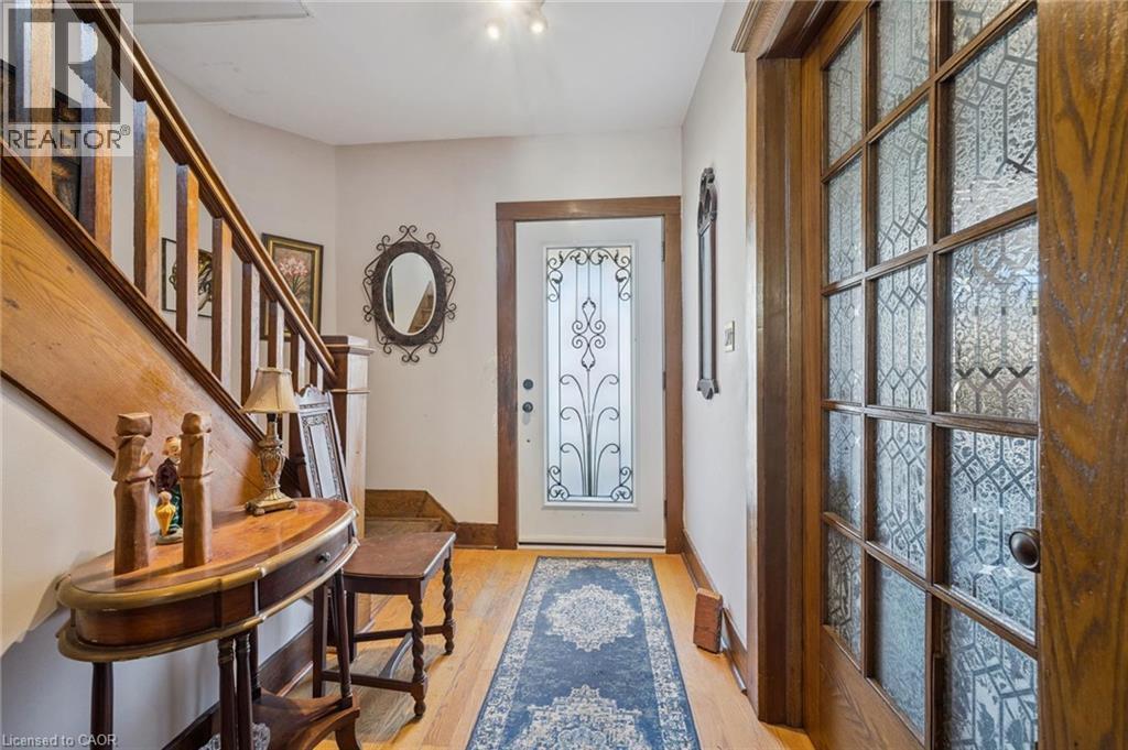 Entryway featuring hardwood flooring, a wood staircase, a white door with decorative glass and ironwork, and a wood-frame door with leaded glass panels - 115 Allen Street E, Waterloo, ON - Indoor Photo Showing Other Room
