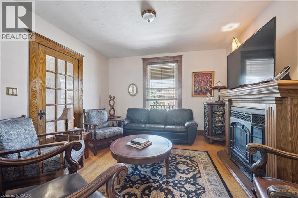 Living area featuring wood-finish flooring, a fireplace with an ornate wood mantel, and a multi-pane glass door with wood trim - 115 Allen Street E, Waterloo, ON - Indoor Photo Showing Living Room With Fireplace