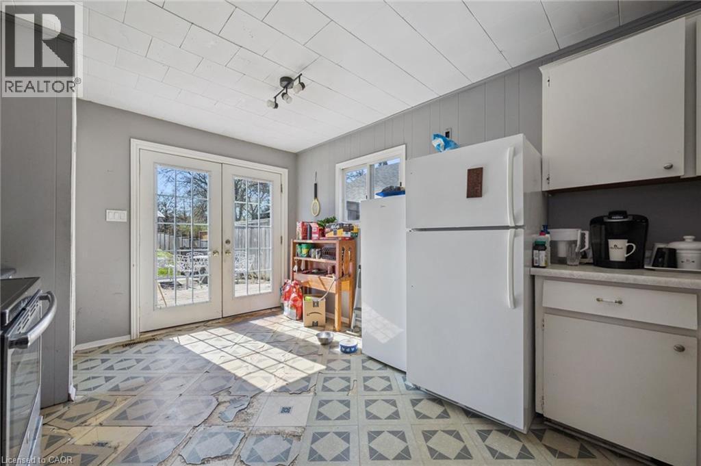 Double French doors leading to the exterior, with patterned floor tiles, white upper and lower cabinetry, and horizontal wall paneling - 115 Allen Street E, Waterloo, ON - Indoor Photo Showing Kitchen
