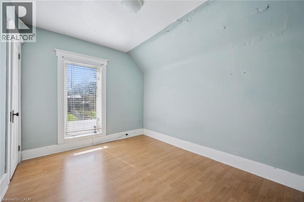 Bright room featuring wood-finish flooring, a single window with blinds, and a white paneled door with dark hardware - 115 Allen Street E, Waterloo, ON - Indoor Photo Showing Other Room