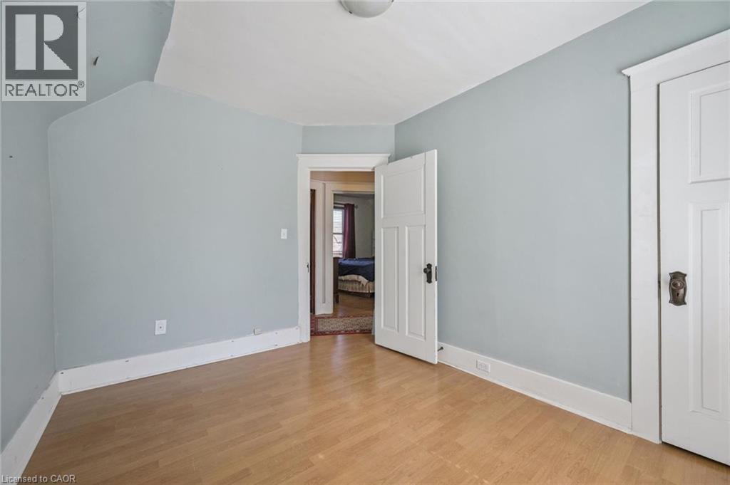 Room featuring wood-finish flooring, light blue wall paint, white baseboards, and white paneled doors with dark hardware - 115 Allen Street E, Waterloo, ON - Indoor Photo Showing Other Room
