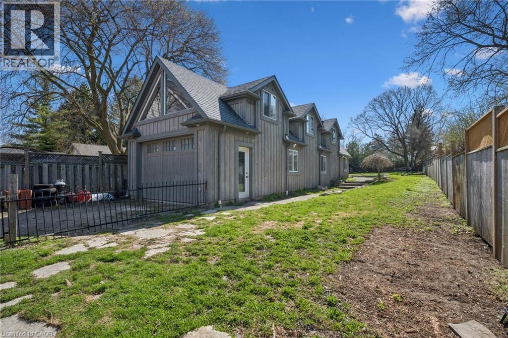 Rear exterior featuring vertical siding, multiple dormer windows, and a detached garage with an A-frame gable - 115 Allen Street E, Waterloo, ON - Outdoor