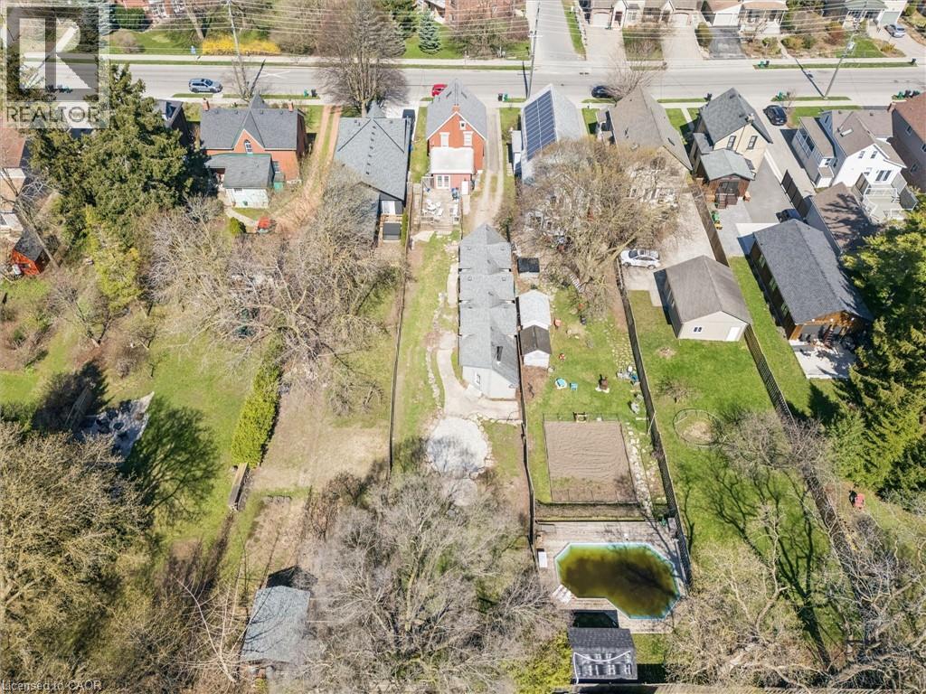 Aerial perspective showcasing multiple residential properties, expansive green spaces, mature trees, and a private pool structure - 115 Allen Street E, Waterloo, ON - Outdoor With View