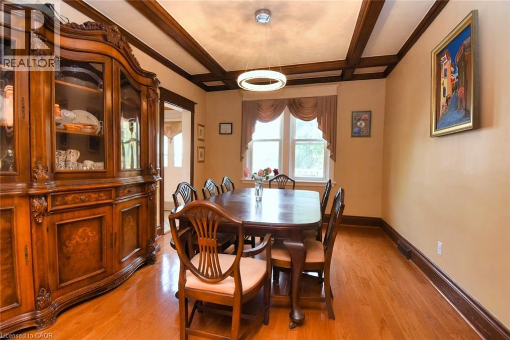 Dining area featuring wood-finish flooring, a coffered ceiling with dark wood beams, and a contemporary circular chandelier - 522 Aberdeen Avenue, Hamilton, ON - Indoor Photo Showing Dining Room