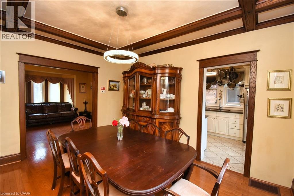 Dining area featuring a contemporary circular chandelier, rich wood-finish flooring, and exposed ceiling beams - 522 Aberdeen Avenue, Hamilton, ON - Indoor Photo Showing Dining Room