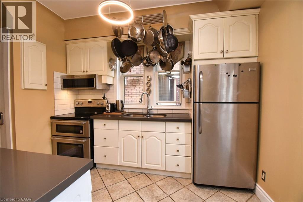 Kitchen featuring ceramic tile flooring, white cabinetry, dark countertops, a stainless steel double oven range, and an over-the-range microwave - 522 Aberdeen Avenue, Hamilton, ON - Indoor Photo Showing Kitchen With Double Sink