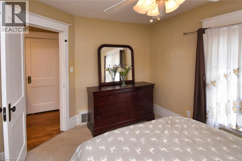 Carpeted room with a ceiling fan light fixture, a window featuring blinds and decorative curtains, and a doorway with a classic paneled door - 522 Aberdeen Avenue, Hamilton, ON - Indoor Photo Showing Bedroom