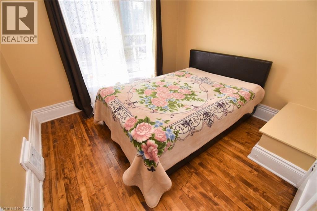Room featuring wood-finish flooring, light-colored walls, white baseboards, and a window with dark drapes - 522 Aberdeen Avenue, Hamilton, ON - Indoor Photo Showing Bedroom
