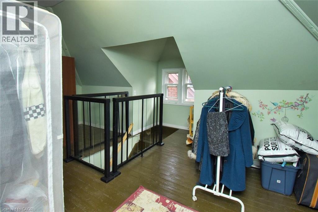 Upper-level room featuring an open staircase with black metal railings, a white framed window, and pitched ceilings - 522 Aberdeen Avenue, Hamilton, ON - Indoor