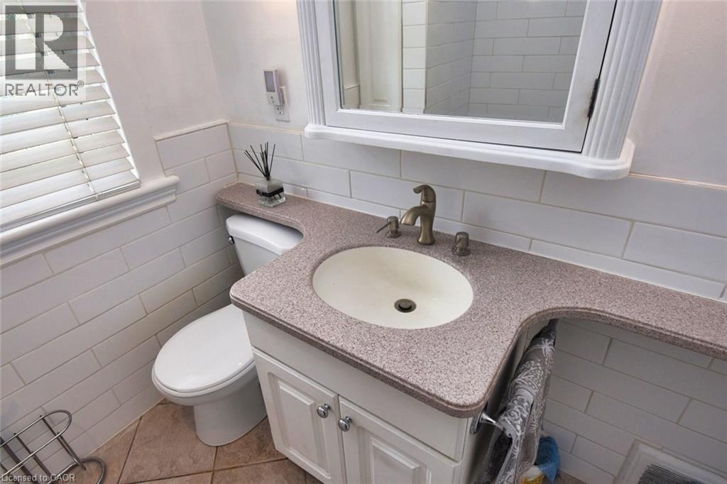Integrated vanity with an oval basin sink, a speckled countertop, and a brushed bronze faucet set - 522 Aberdeen Avenue, Hamilton, ON - Indoor Photo Showing Bathroom