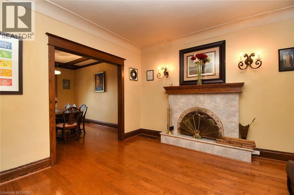 Hardwood flooring throughout featuring a tiled fireplace with a wood mantle and ornate sconces - 522 Aberdeen Avenue, Hamilton, ON - Indoor With Fireplace