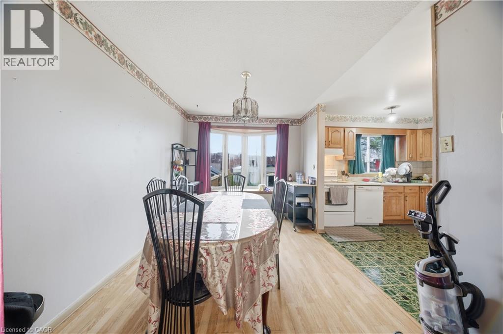 Dining area featuring wood-finish flooring, a bay window with purple drapes, and an overhead chandelier - 116 Gainsborough Road, Hamilton, ON - Indoor Photo Showing Dining Room