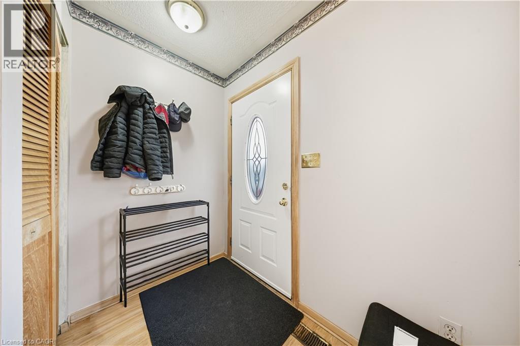Entryway featuring a white door with an oval decorative glass insert, wood-finish flooring, a louvered closet door, and a flush-mount ceiling light - 116 Gainsborough Road, Hamilton, ON - Indoor Photo Showing Other Room