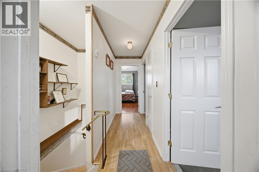 Hallway featuring wood-finish flooring, white walls, and a brass-tone handrail leading to a lower level - 116 Gainsborough Road, Hamilton, ON - Indoor Photo Showing Other Room