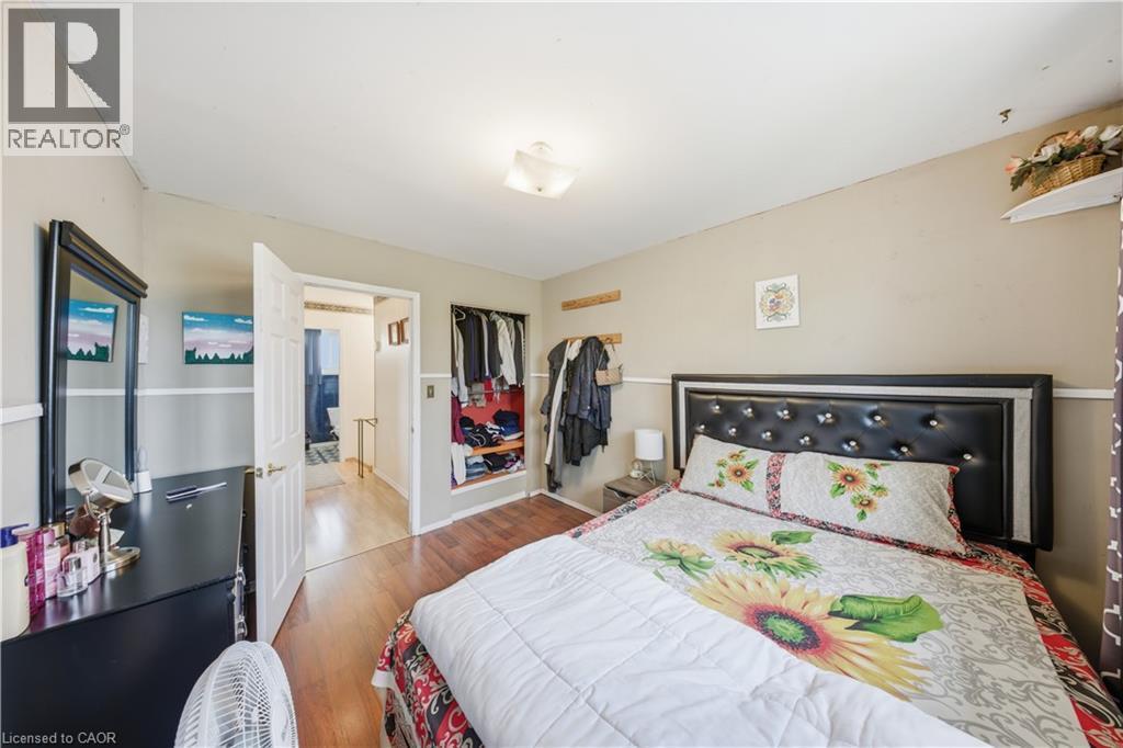 Bedroom featuring wood-finish flooring, two-tone painted walls, a built-in open closet with shelving, and a flush-mount ceiling light fixture - 116 Gainsborough Road, Hamilton, ON - Indoor Photo Showing Bedroom
