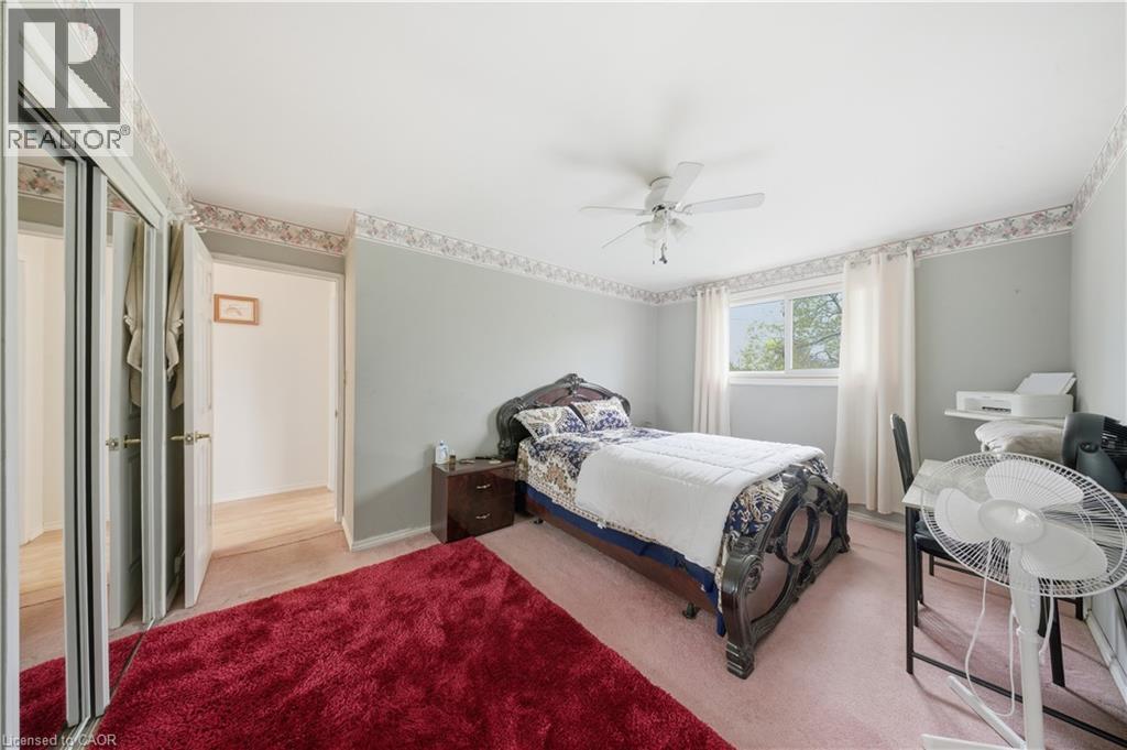 Bedroom featuring a ceiling fan, wall-to-wall carpeting, and a window with white curtains - 116 Gainsborough Road, Hamilton, ON - Indoor Photo Showing Bedroom