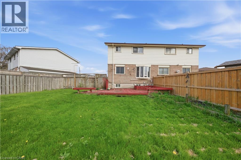 Expansive grassy lawn with a red-stained wooden deck - 116 Gainsborough Road, Hamilton, ON - Outdoor