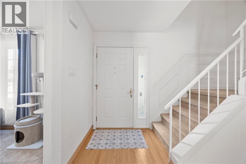 Entryway featuring a paneled door with a sidelight, hardwood flooring, and a carpeted staircase with white railings - 277 Blackacres Boulevard, London, ON - Indoor Photo Showing Other Room