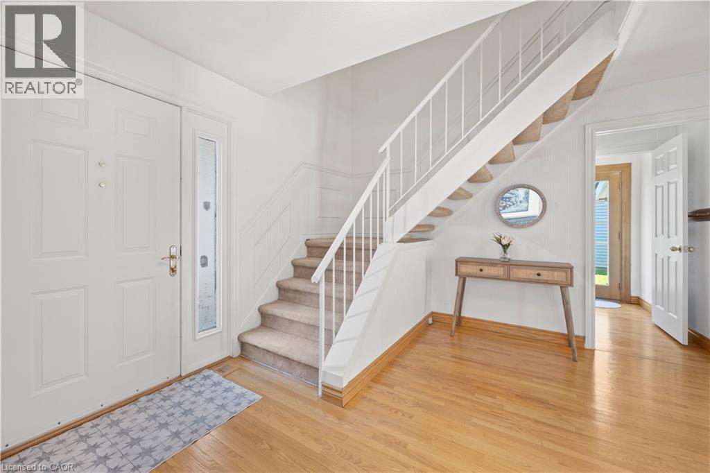 Entry foyer featuring a paneled door with a sidelight, a carpeted staircase with white railings, light wood-finish flooring, and white painted walls - 277 Blackacres Boulevard, London, ON - Indoor Photo Showing Other Room