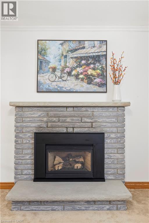 Fireplace featuring a light grey brick surround, a black firebox, a stone mantel, and a matching stone hearth - 277 Blackacres Boulevard, London, ON - Indoor Photo Showing Living Room With Fireplace