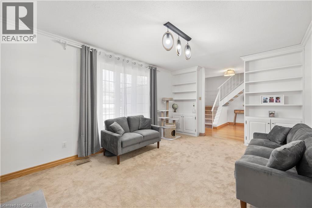 Carpeted living area featuring white walls, crown molding, and a three-light linear pendant fixture - 277 Blackacres Boulevard, London, ON - Indoor
