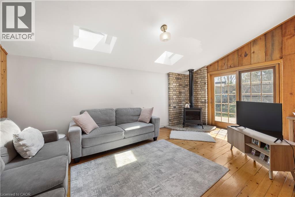 Living area featuring light wood-finish flooring, two ceiling skylights, and a gas fireplace with a brick surround - 277 Blackacres Boulevard, London, ON - Indoor Photo Showing Living Room With Fireplace