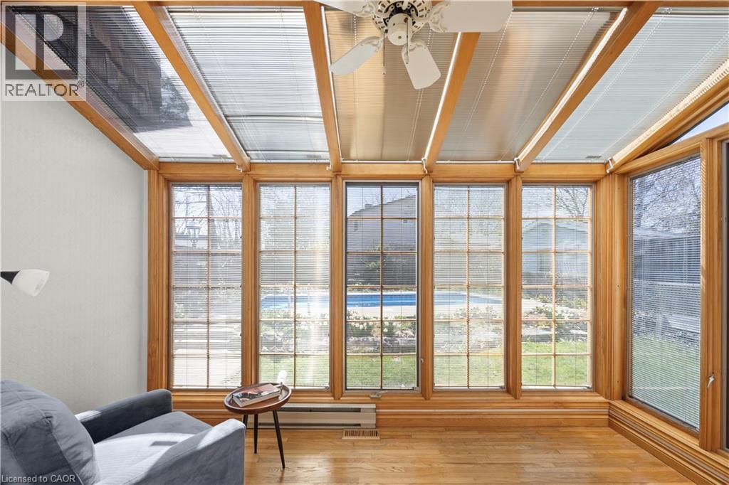Sunroom featuring wood-finish flooring, extensive natural wood window frames, and ceiling panels with integrated blinds - 277 Blackacres Boulevard, London, ON - Indoor Photo Showing Other Room